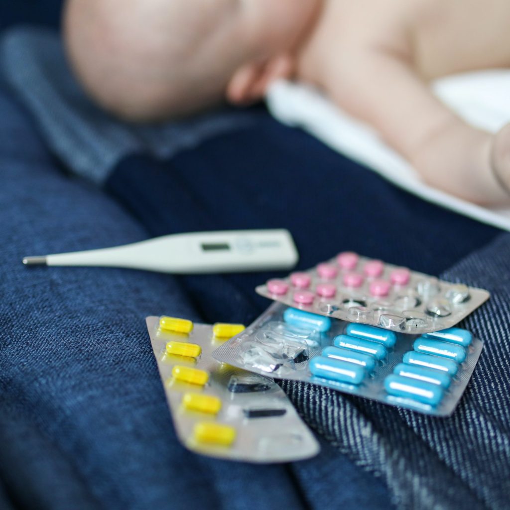 Medication and a thermometer on a bed